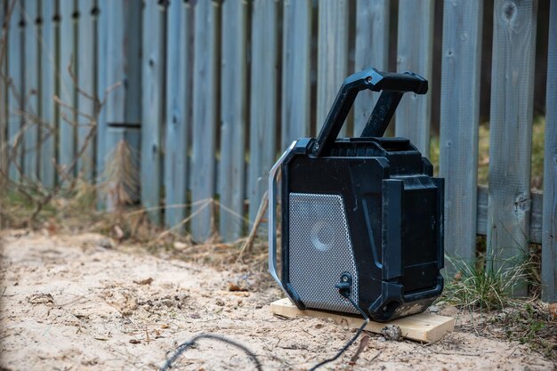 A portable generator running in the backyard of a house, with a visible extension cord plugged into it. The generator is placed on a flat, stable surface, away from the house. The scene suggests a practical solution for maintaining power supply during an outage.