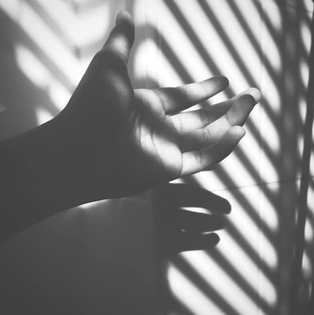 A close-up shot of hands gently resting in a meditative pose, symbolizing peace and mindfulness. The background is blurred to emphasize the hands and their gesture.