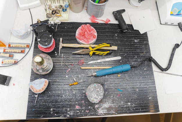 A cosplayer meticulously shaping a piece of EVA foam for an intricate armor component, with various crafting tools and reference images laid out on a workbench.