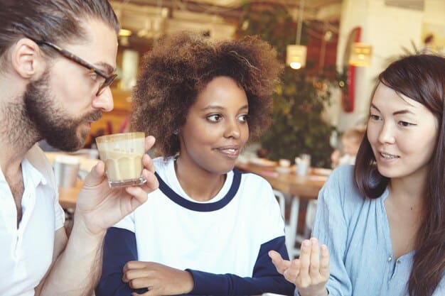A group of diverse people laughing and talking warmly over coffee, illustrating strong social connections.