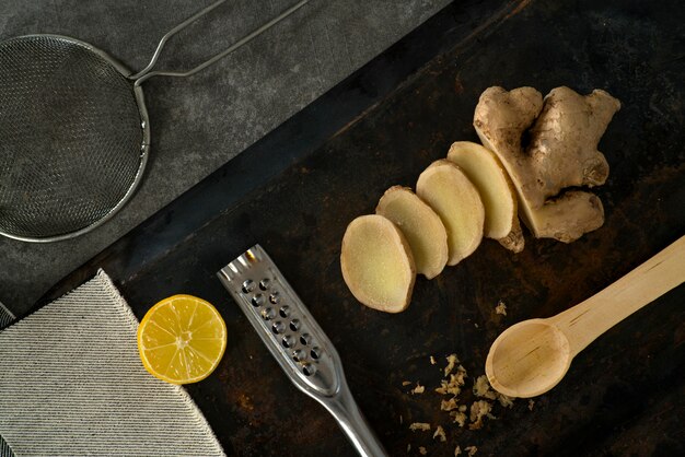 A close-up shot of freshly sliced ginger root next to a grater, with a cup of steaming ginger tea in the background. The ginger is brightly lit, highlighting its texture and the natural oils on its surface, emphasizing its health benefits and natural remedy for inflammation.